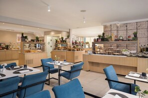 A modern restaurant with blue chairs, wooden tables, and a kitchen area with various food items and plants. - Bellevue Maradiso Village by Aminess  (Orebic)