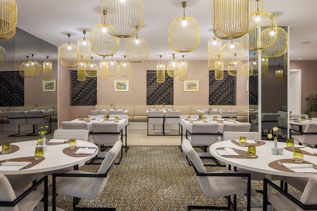 A hotel dining area with round tables, chairs, and pendant lighting.