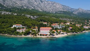 A coastal town with buildings along the shoreline, a prominent red and white building, and mountainous terrain in the background. - Bellevue Maradiso Village by Aminess  (Orebic)