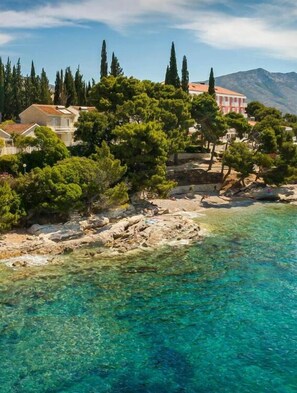 A coastal property with clear turquoise waters, rocky shoreline, and a backdrop of mountains. - Bellevue Maradiso Village by Aminess  (Orebic)