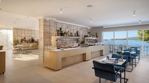 A modern kitchen with a stone backsplash, a bar area, and a dining space with a view of the sea. - Bellevue Maradiso Village by Aminess  (Orebic)