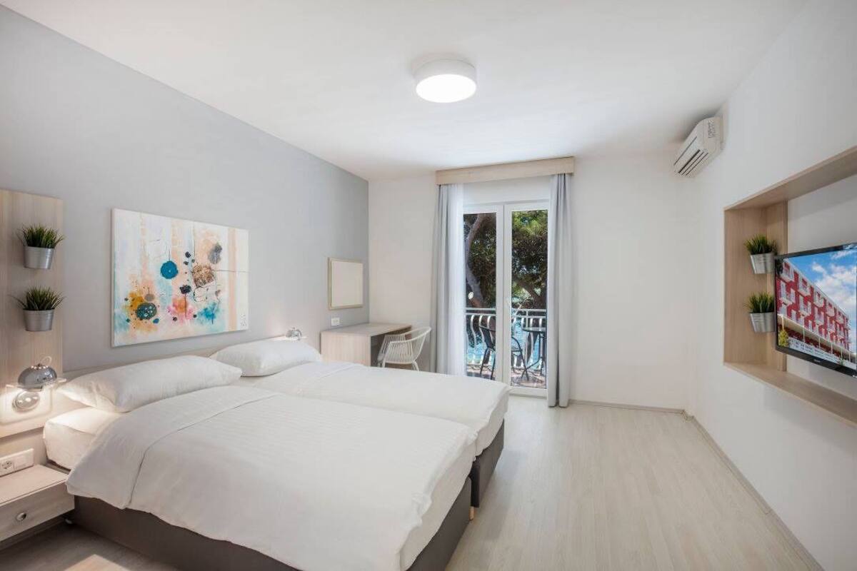 Un dormitorio moderno con una cama grande, un escritorio, una silla y un balcón con vistas al exterior.