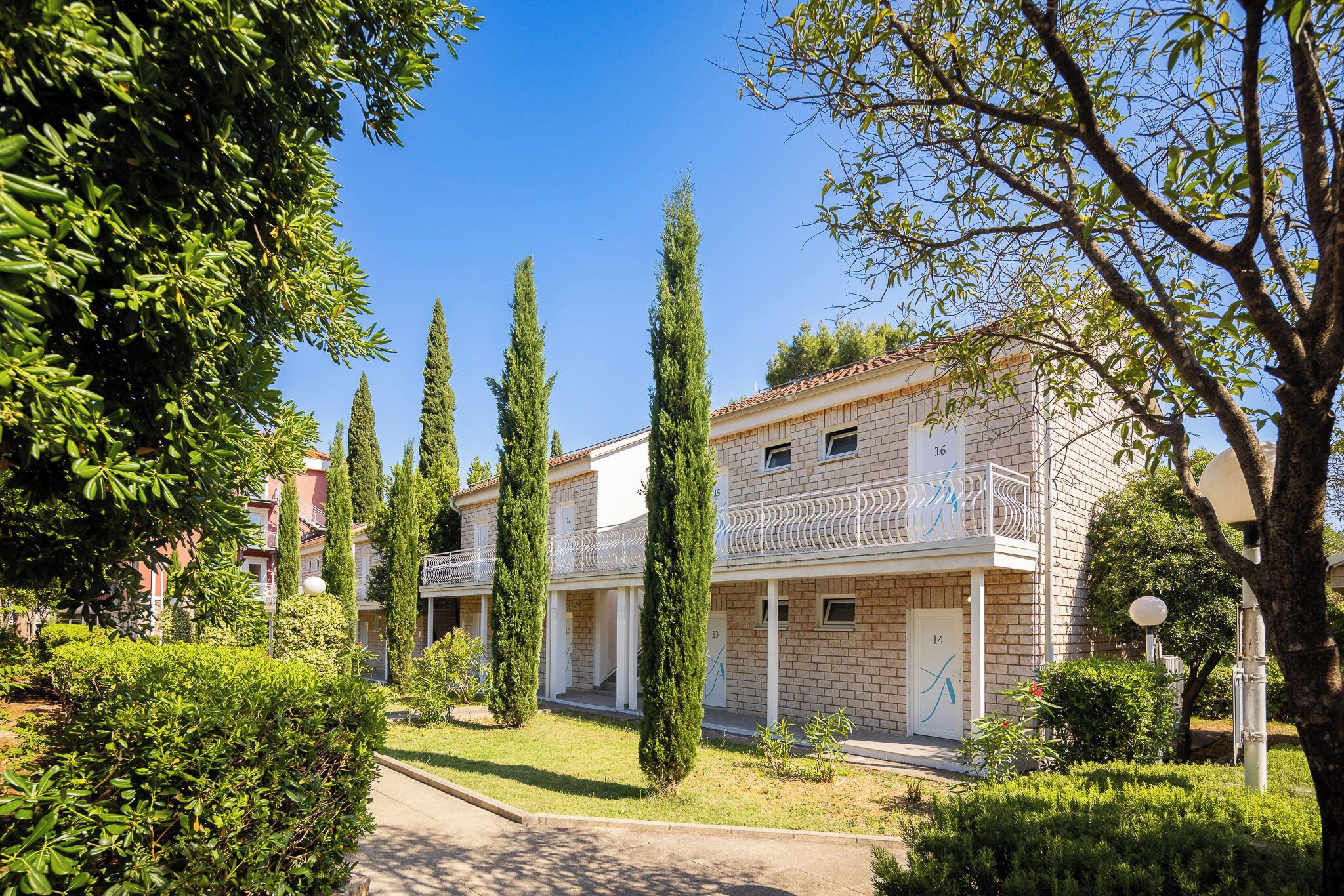A building with numbered doors, a covered outdoor area, and a well-maintained garden.