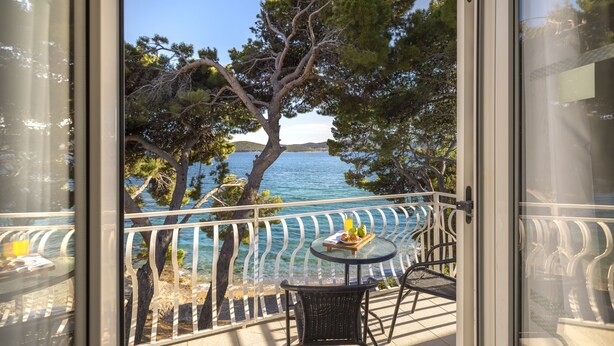 A balcony with a clear view of the sea, a table with a tray of food, and a chair. - Bellevue Maradiso Village by Aminess  (Orebic)