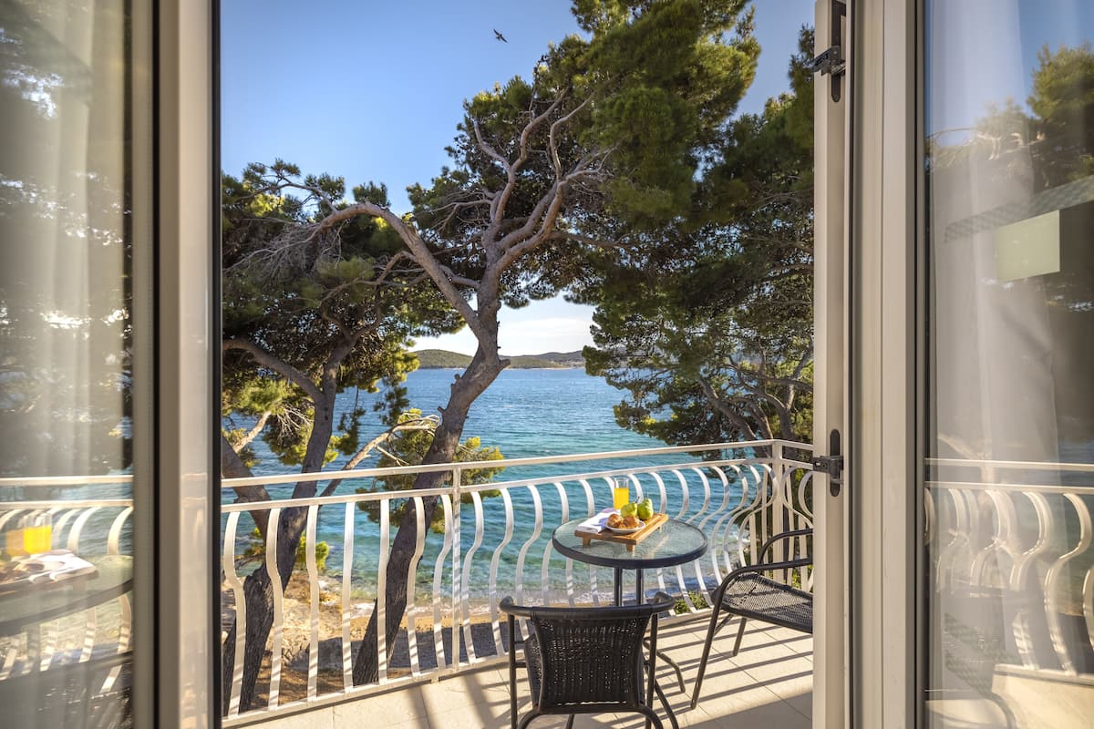 Un balcón con vistas despejadas al mar, una mesa con una bandeja de comida y una silla.