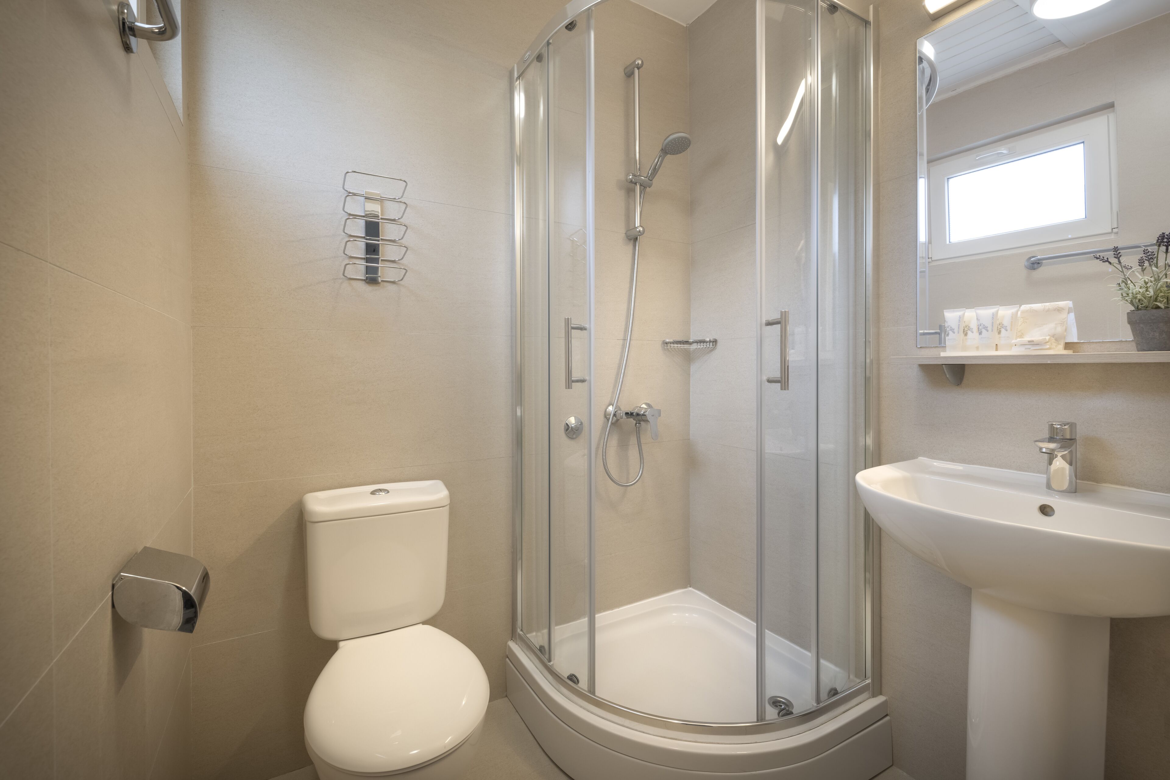 Un bagno moderno con doccia vetrata, un water bianco e un lavandino con uno specchio sopra.
