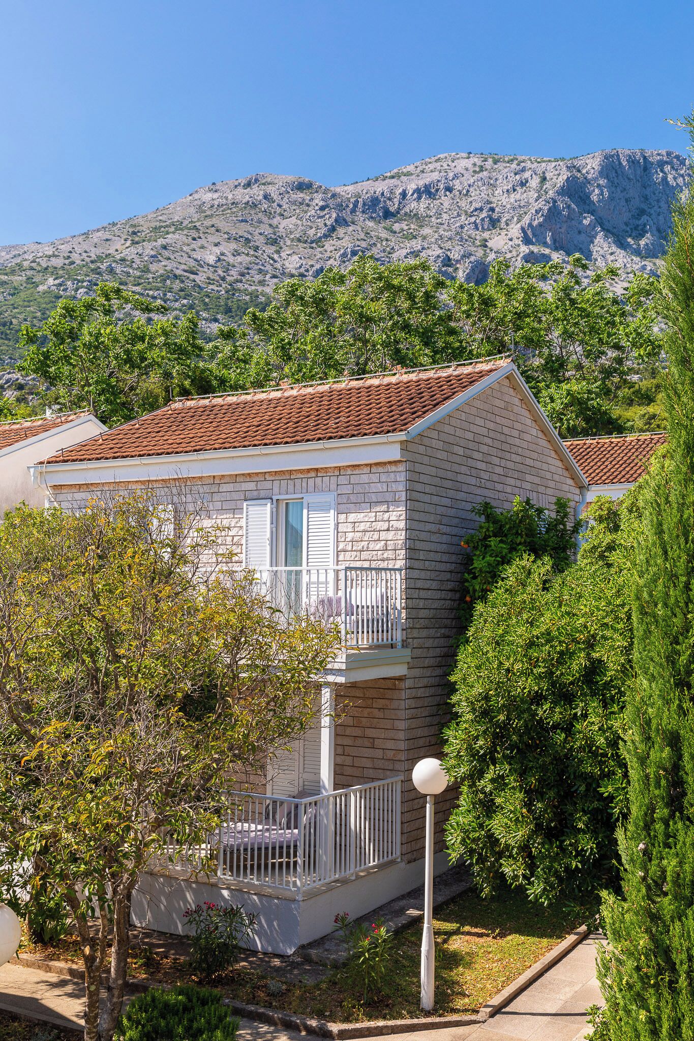 Ein zweistöckiges Haus mit Ziegeldach, einem Balkon und Blick auf eine Berglandschaft.