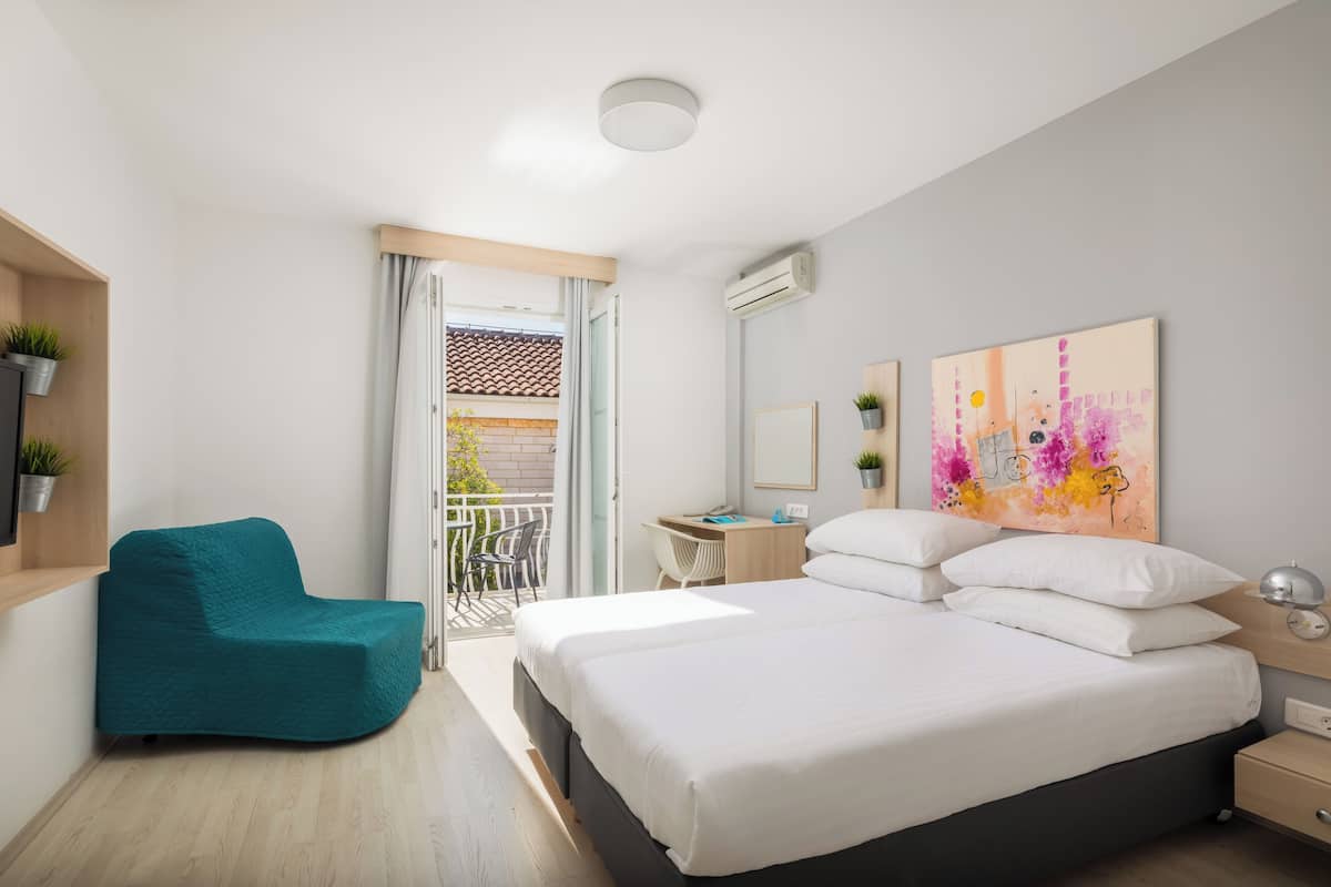 Un dormitorio moderno con cama, escritorio, silla y balcón.