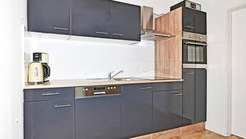 A modern kitchen with dark cabinets, a wooden countertop, a built-in oven, and a coffee maker.