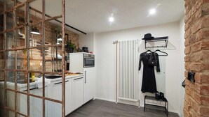 Una cocina con armarios blancos, una estufa y una pata para colgar ollas.