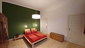 Un dormitorio con cama, lámparas de noche, un banco de madera, un armario y una puerta.
