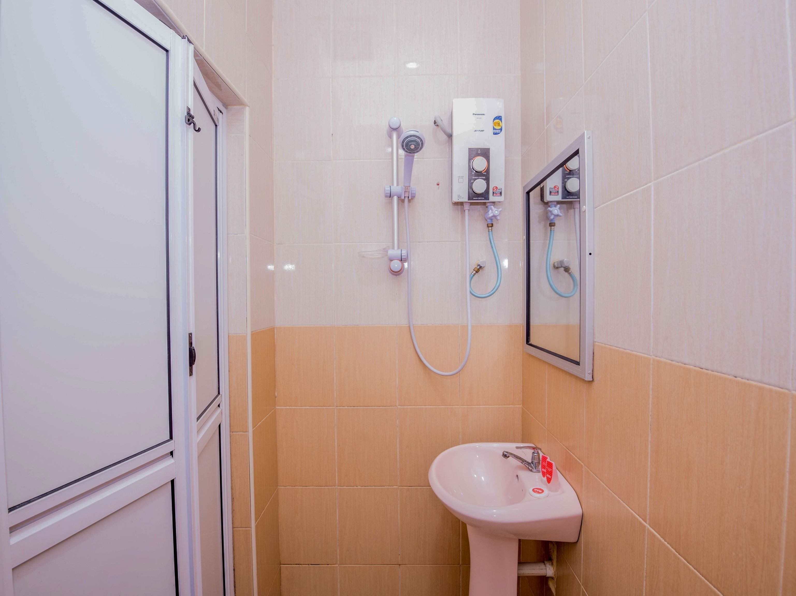 Un baño con lavamanos blanco, espejo y cabina de ducha con panel de control.