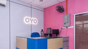 A reception desk with a 'OYO' sign, a blue chair, a computer, and a small fan on the wall. - Hotel O Rg Motel (Changlun)