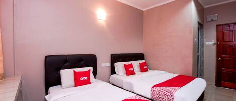 Habitación de hotel con dos camas, cada una con una colcha roja y blanca y almohadas a juego.