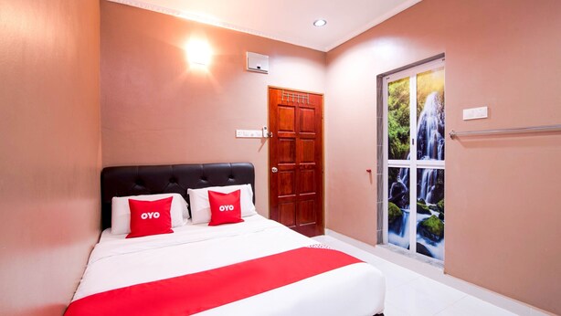 A hotel room with a large bed, a wooden door, and a view of a waterfall through a glass door. - Hotel O Rg Motel (Changlun)