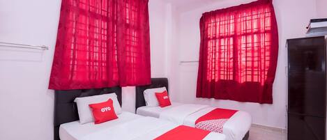 A hotel room with two beds, red curtains, white bedding, and a black wardrobe.