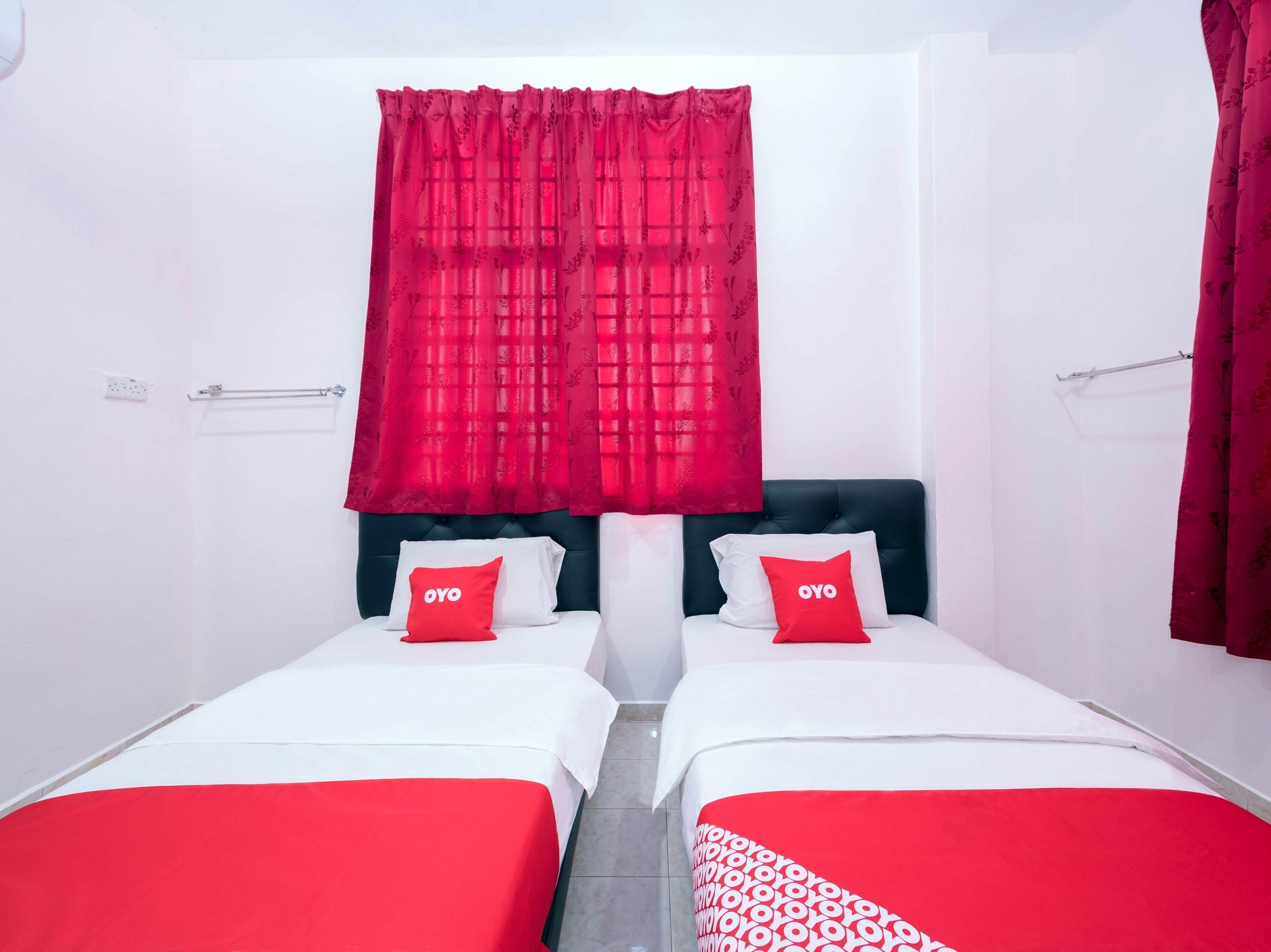 A hotel room with two beds, each with a red and white bedspread and matching pillows.