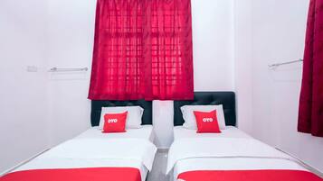 A hotel room with two beds, each with a red and white bedspread and matching pillows.
