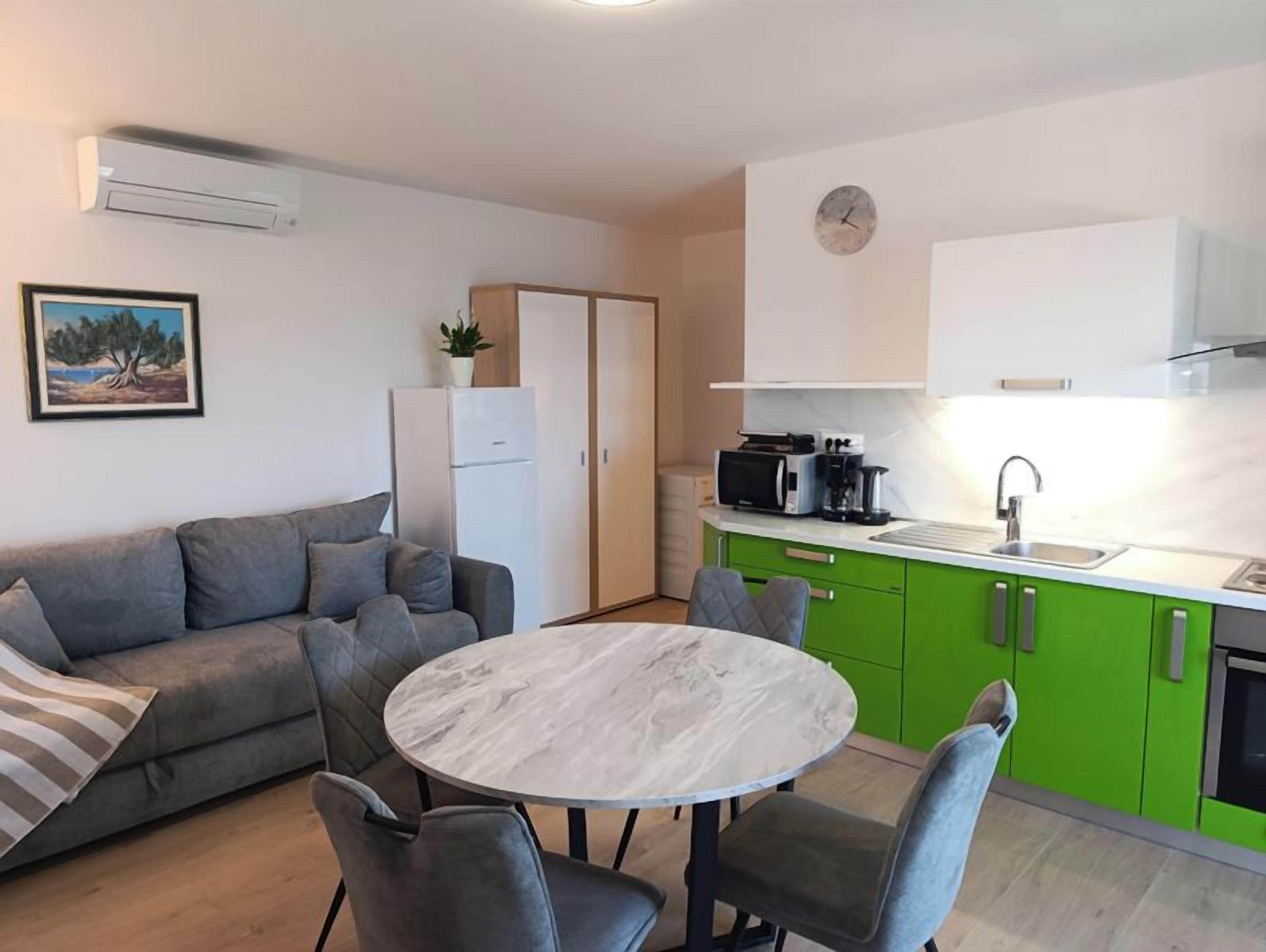 Un espacio habitable compacto con sofá, una mesa de comedor con sillas, una zona de cocina con microondas y refrigerador.