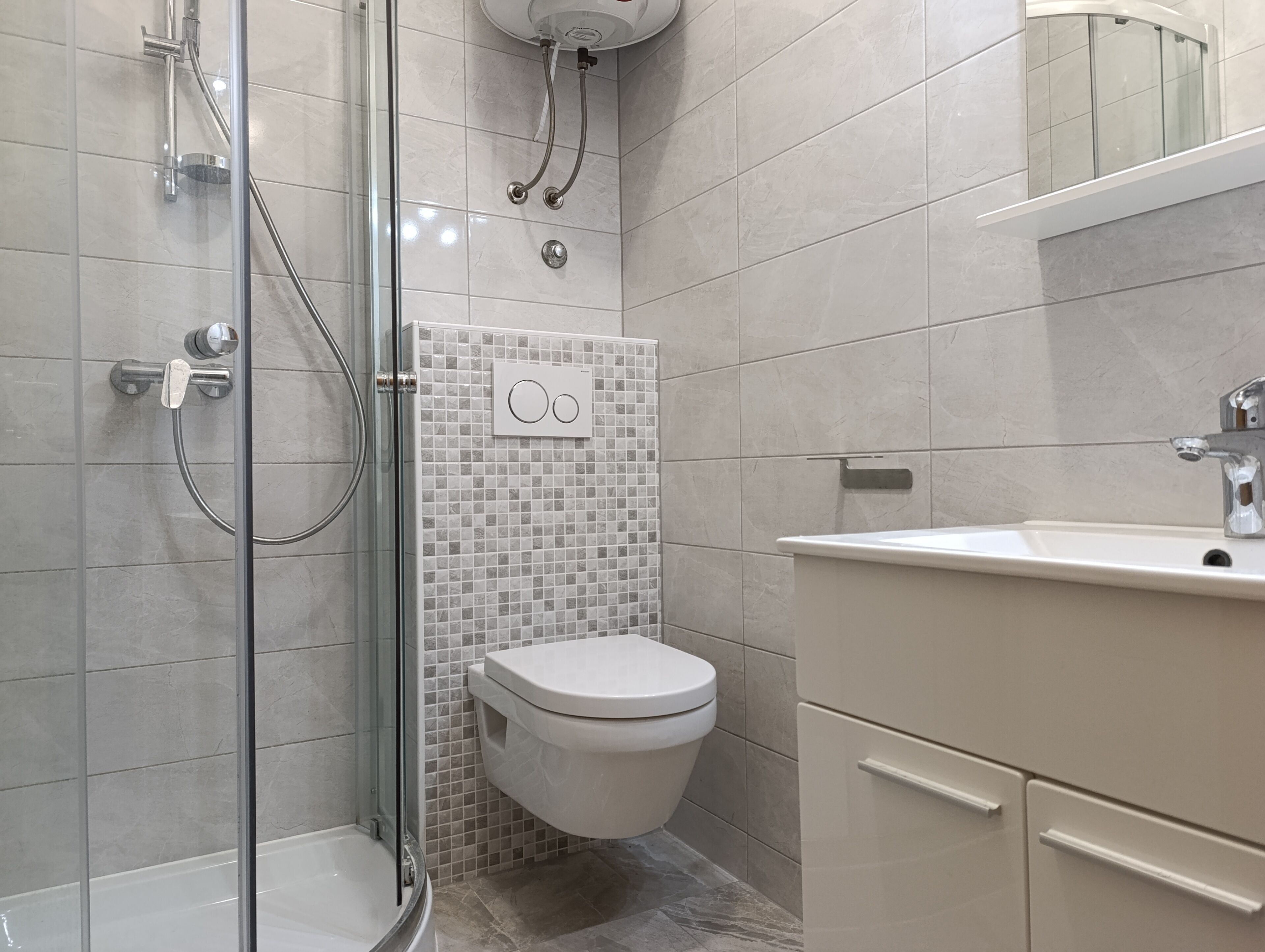 A modern bathroom with a glass-enclosed shower, a toilet, and a sink with a mirror above it.