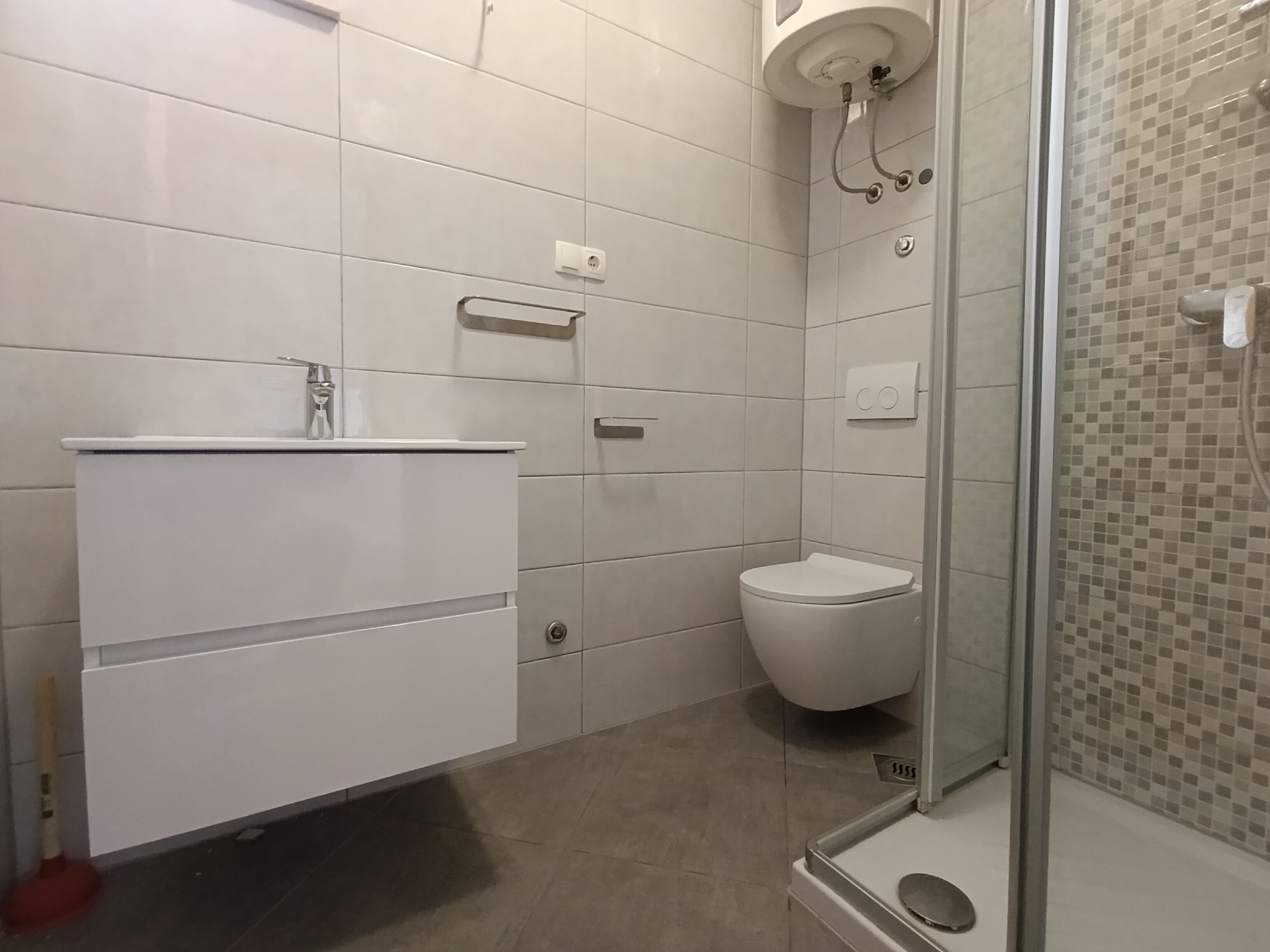Een badkamer met een wit wastafel, toilet en douche.