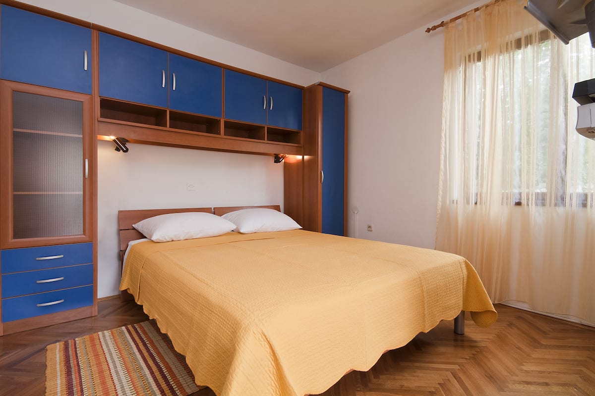 A bedroom with a bed, a wardrobe, and a window with curtains.