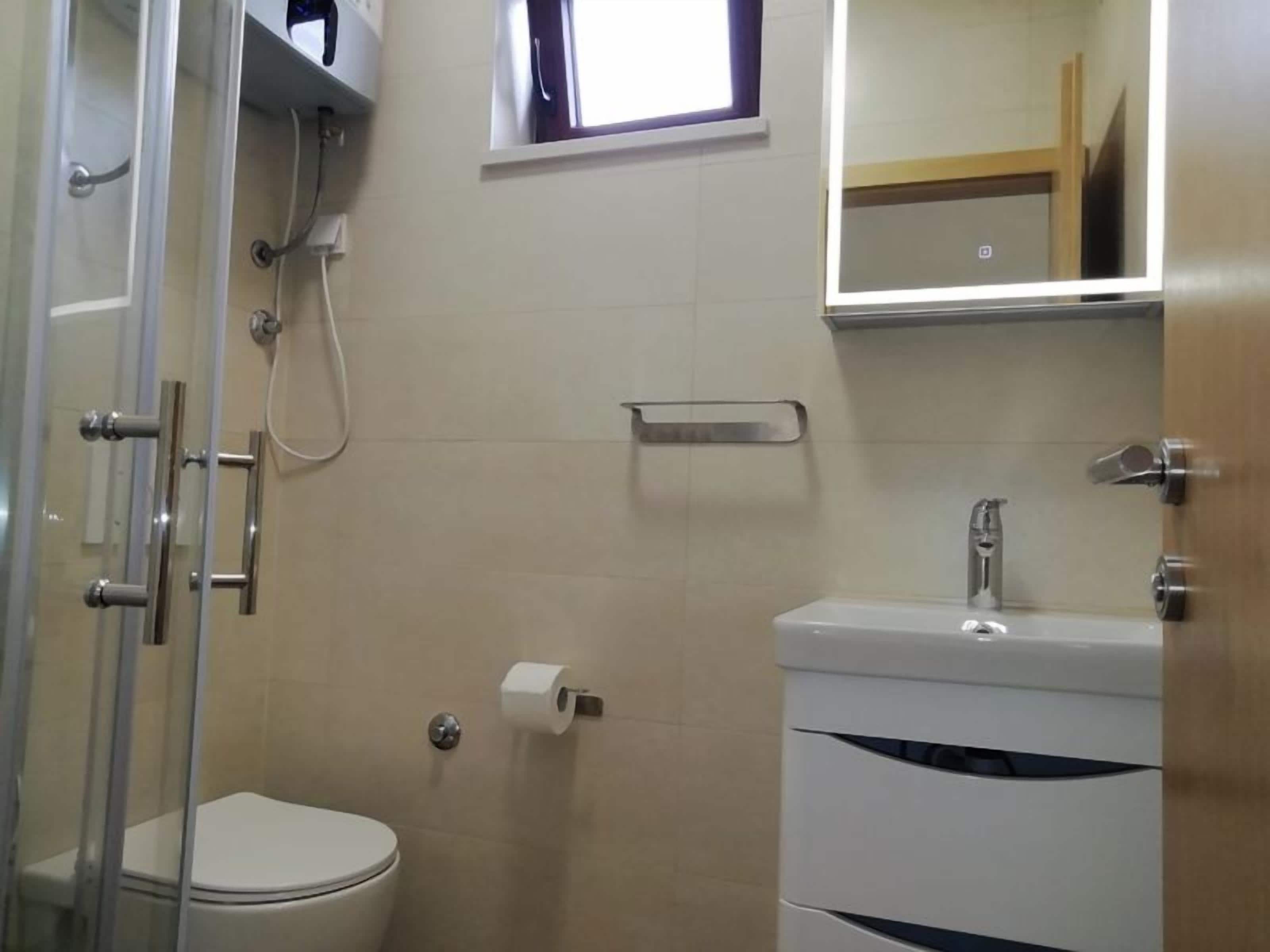 Un baño con inodoro, lavamanos y cabina de ducha.