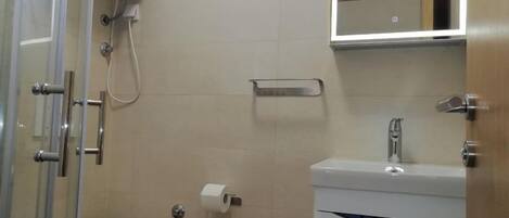 Un baño con inodoro, lavamanos y cabina de ducha.