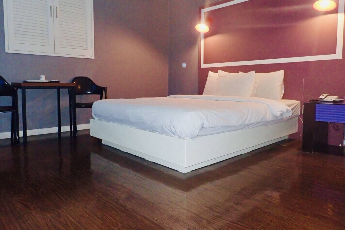 A hotel room with a large bed, a desk, and a chair.
