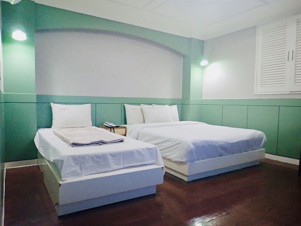 Une chambre avec deux lits simples, une petite table de chevet avec un téléphone et un luminaire fixé au mur.