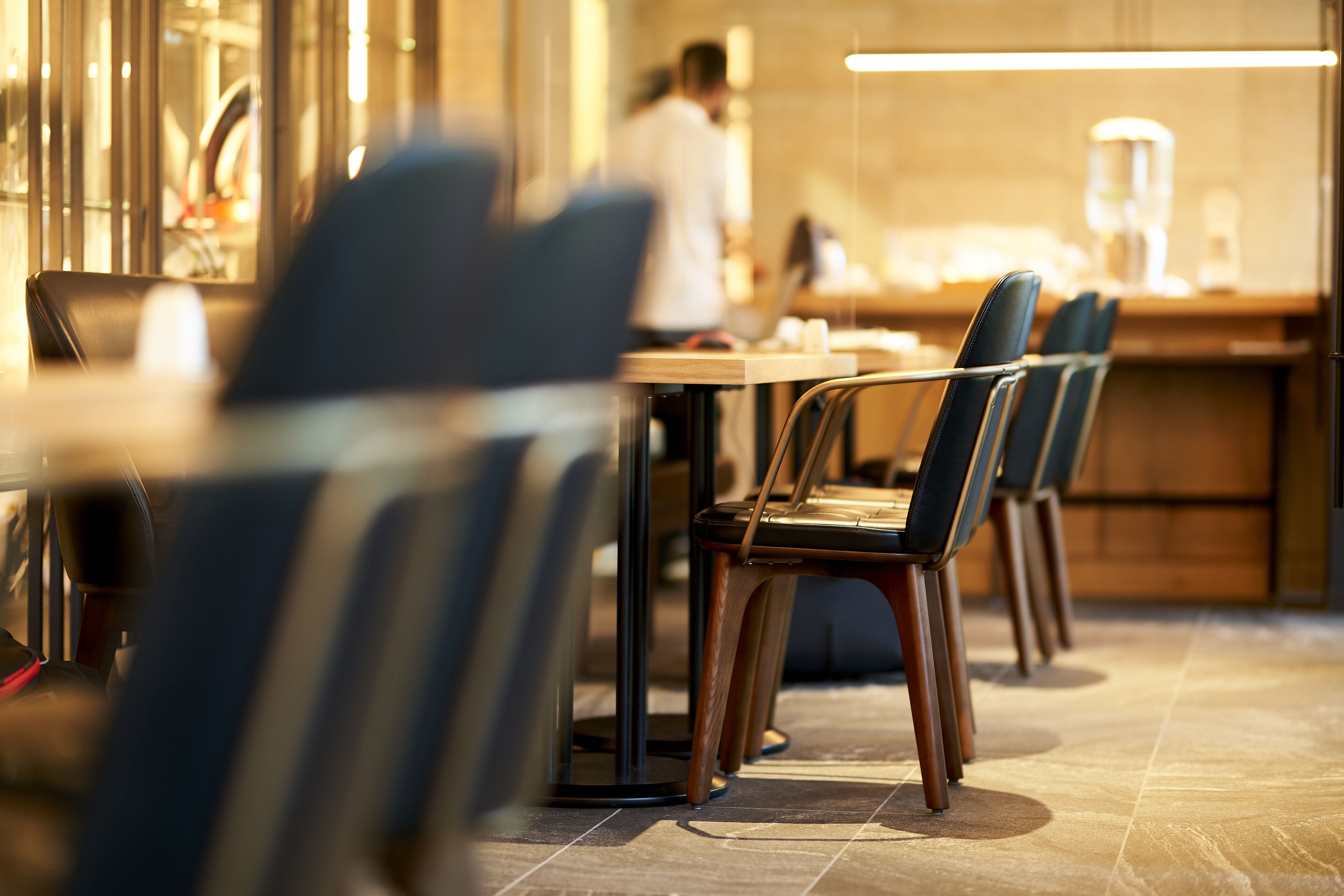 Un interior de restaurante moderno con una larga barra y varias sillas oscuras.