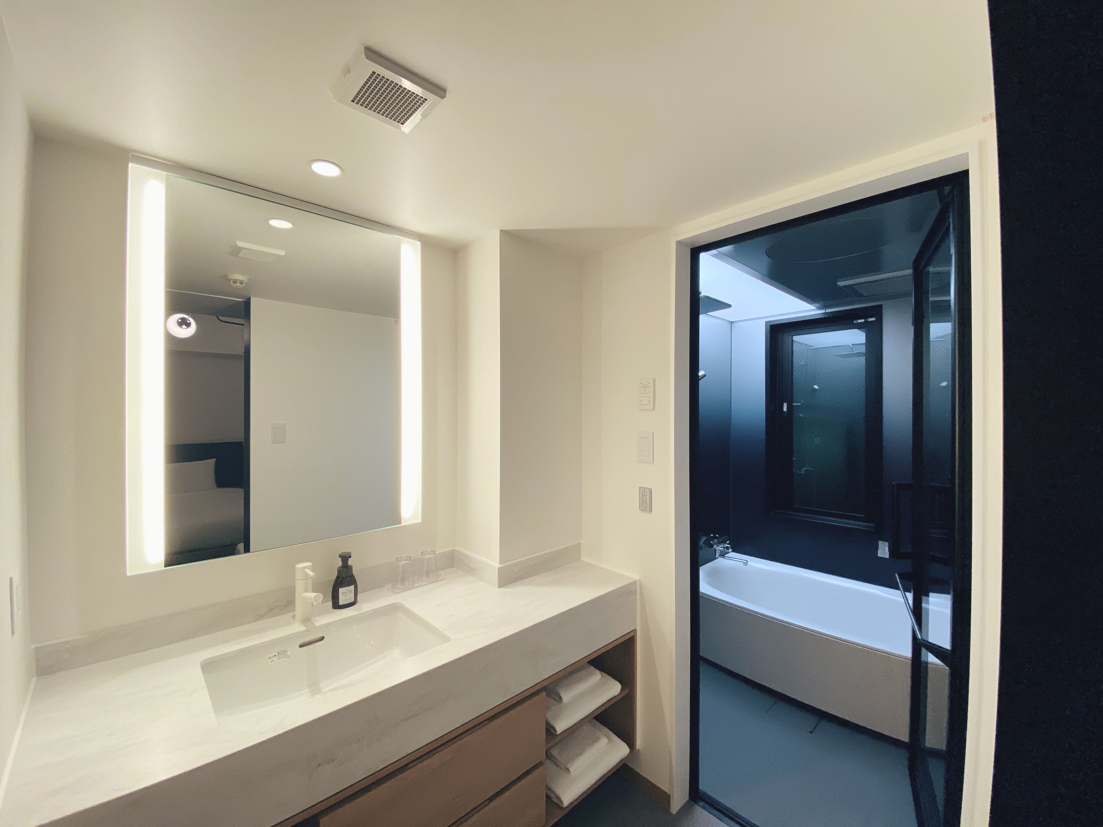 A modern bathroom with a large mirror, a sink, and a glass-enclosed shower area.