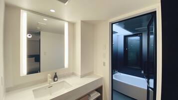 A modern bathroom with a large mirror, a sink, and a glass-enclosed shower area.