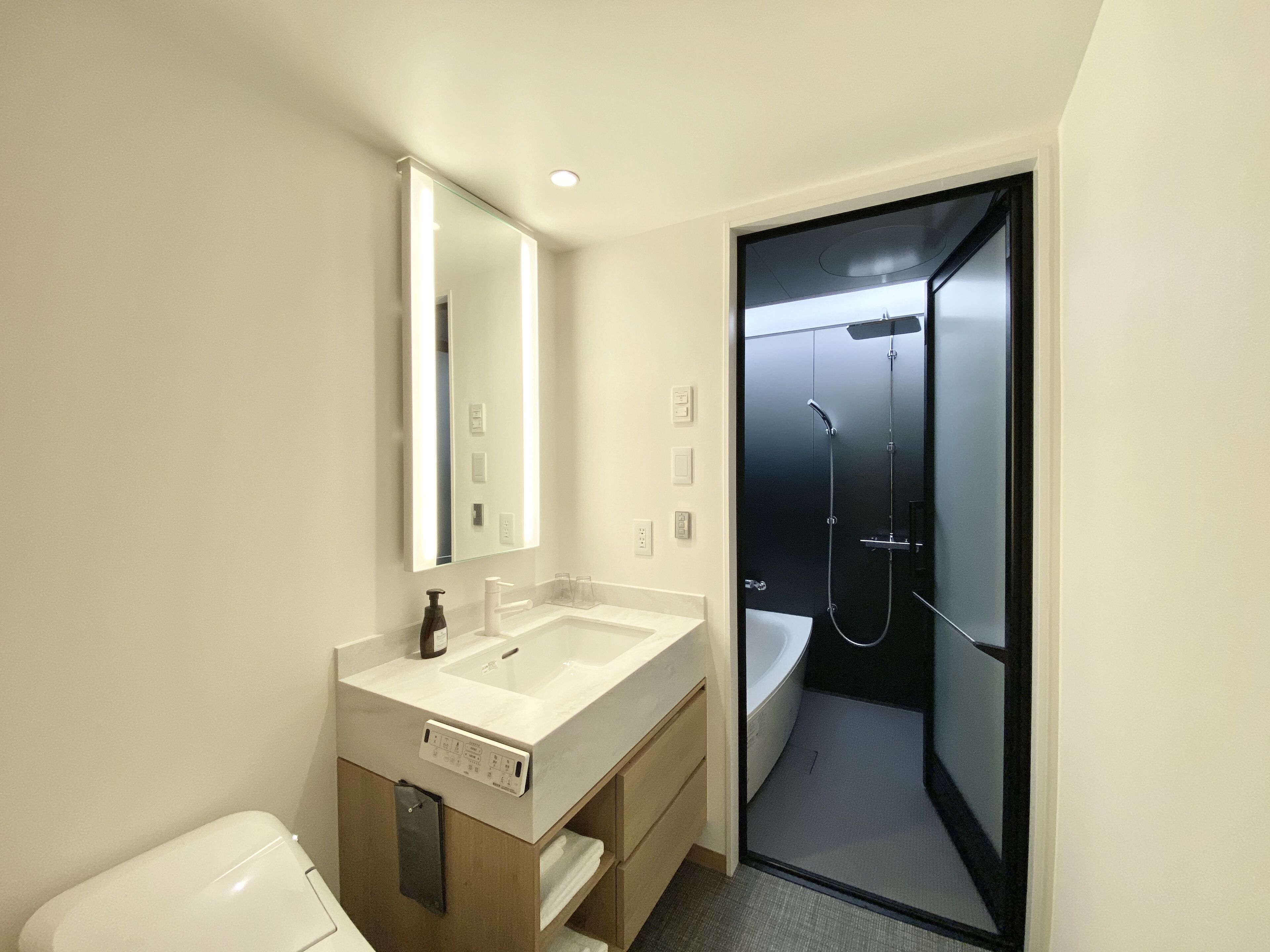 A modern bathroom with a white sink, mirror, and a glass-enclosed shower.