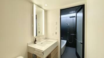 A modern bathroom with a white sink, mirror, and a glass-enclosed shower.
