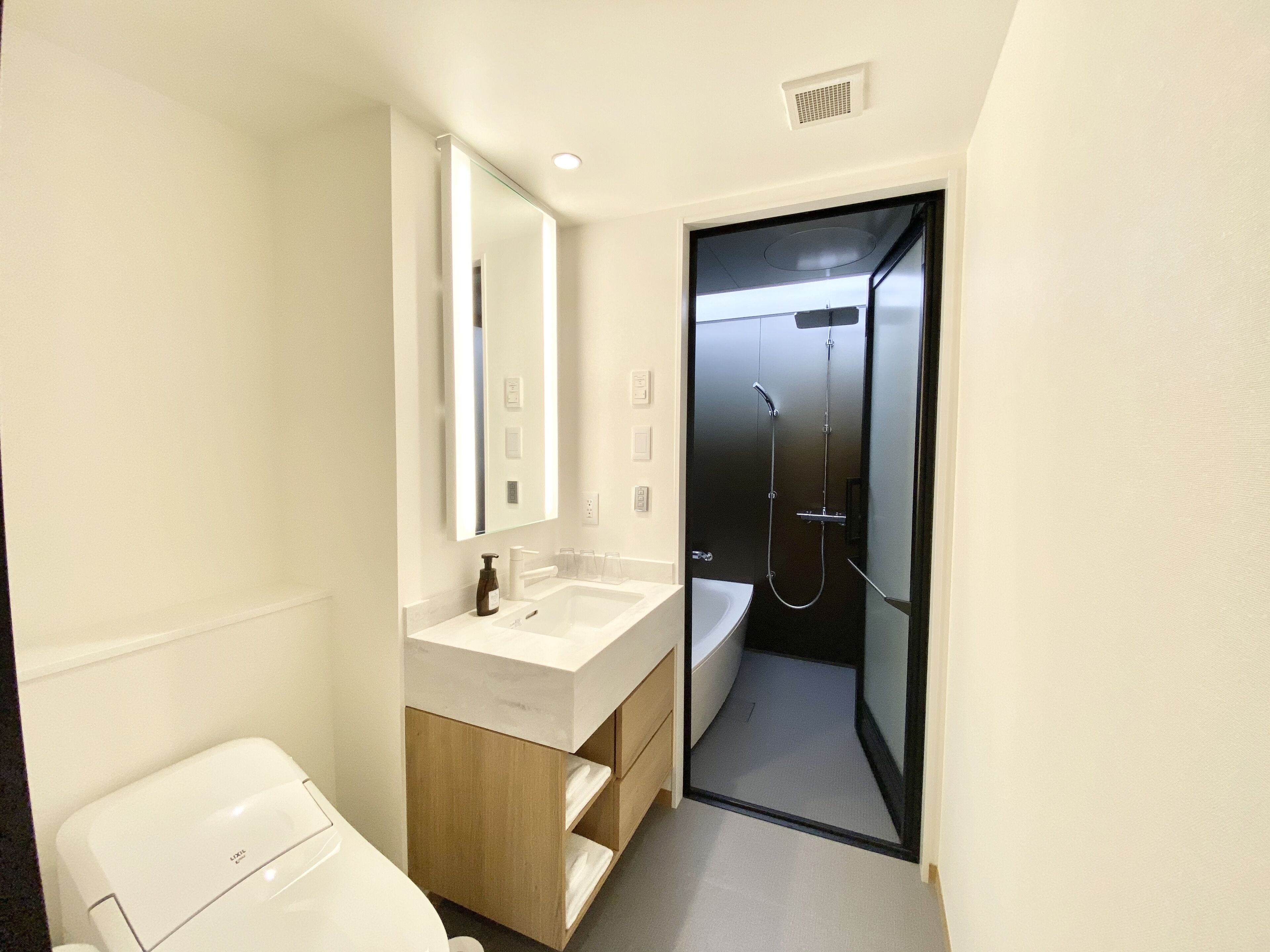 Une salle de bain moderne avec un lavabo blanc, un miroir et une douche.