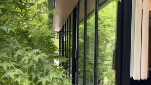 Un couloir aux murs de verre, doté d’un sol carrelé et d’un espace détente avec une table et des chaises.
