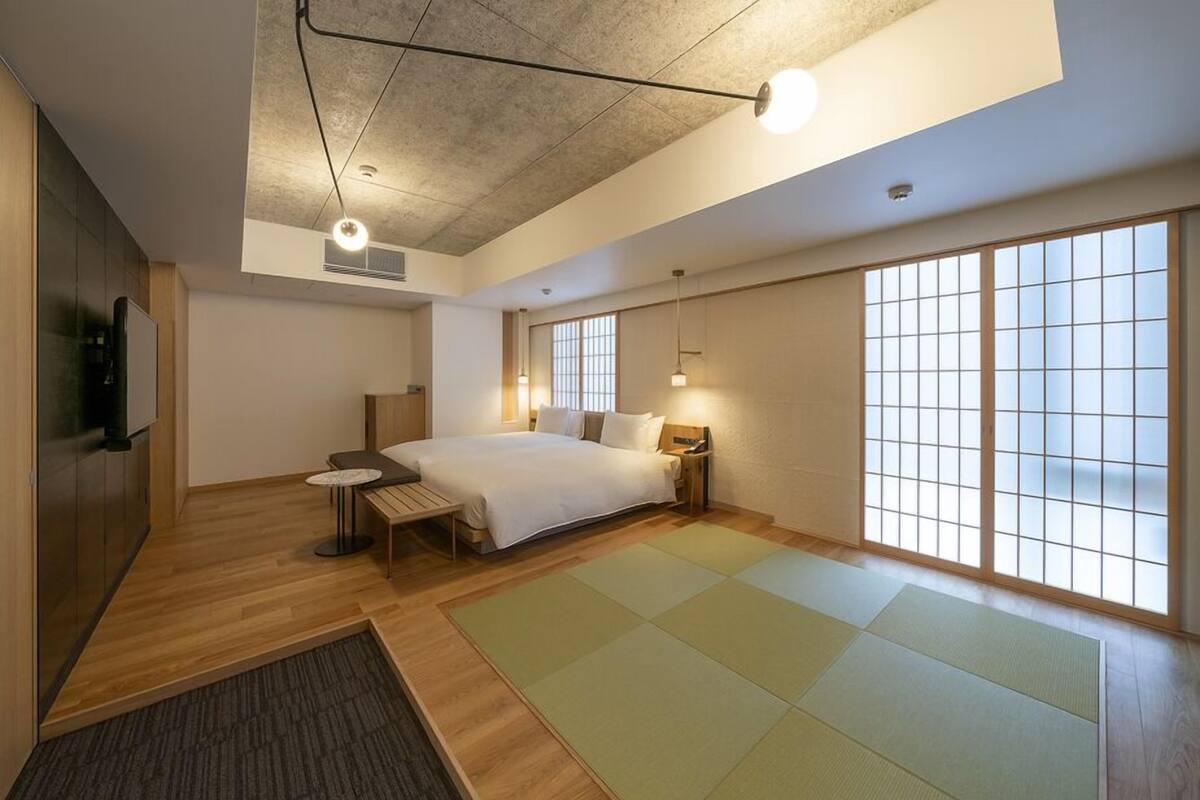 Una habitación de hotel moderna con una cama grande, una mesita, un televisor y puertas correderas.