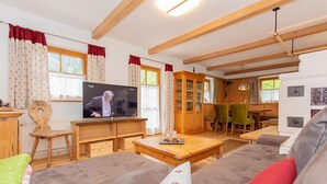 Un salon confortable avec un téléviseur, des meubles en bois et un coin repas.
