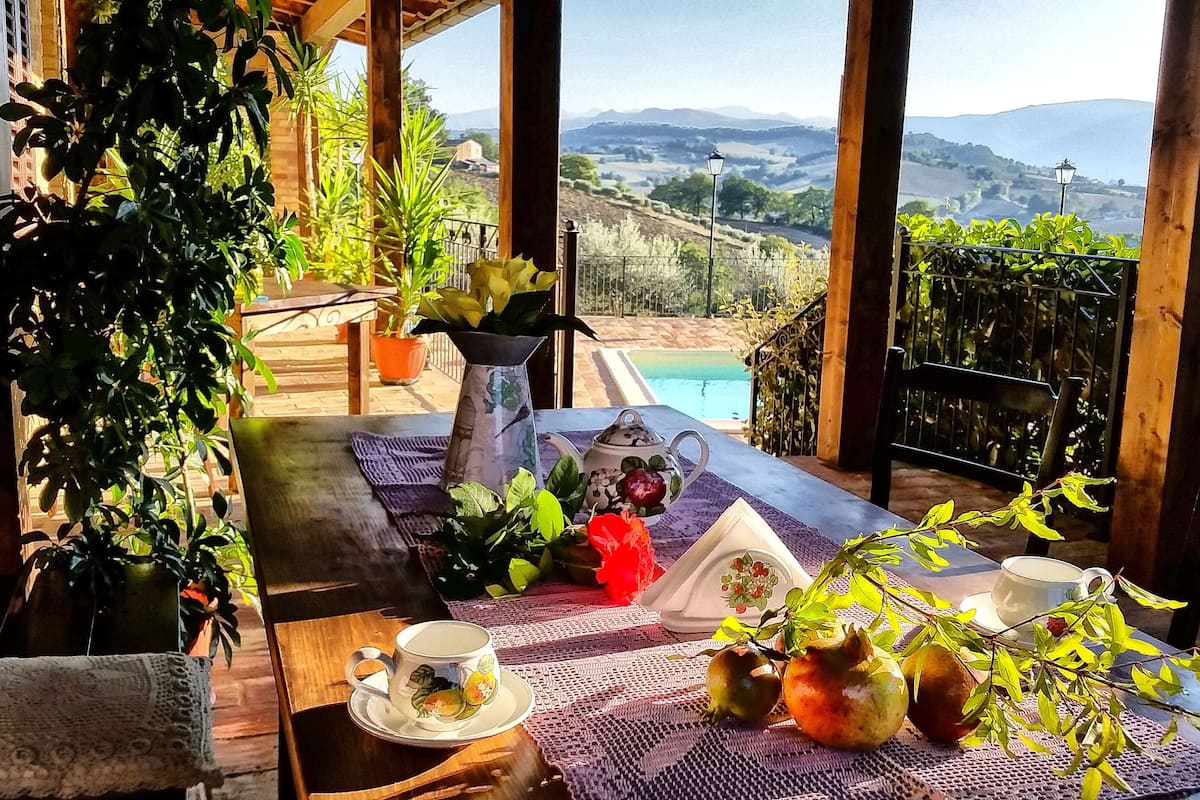 Uma área de estar aconchegante ao ar livre, com vista para uma piscina e montanhas.
