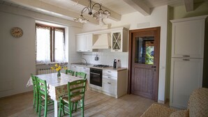 Una cocina con armarios blancos, una puerta de madera y una mesa de comedor con sillas.