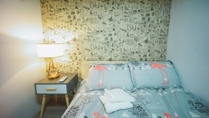 A hotel room with a bed featuring a geometric pattern and a wall covered in newspaper clippings. - Shanghai Rainbow No.35 (Shanghai)