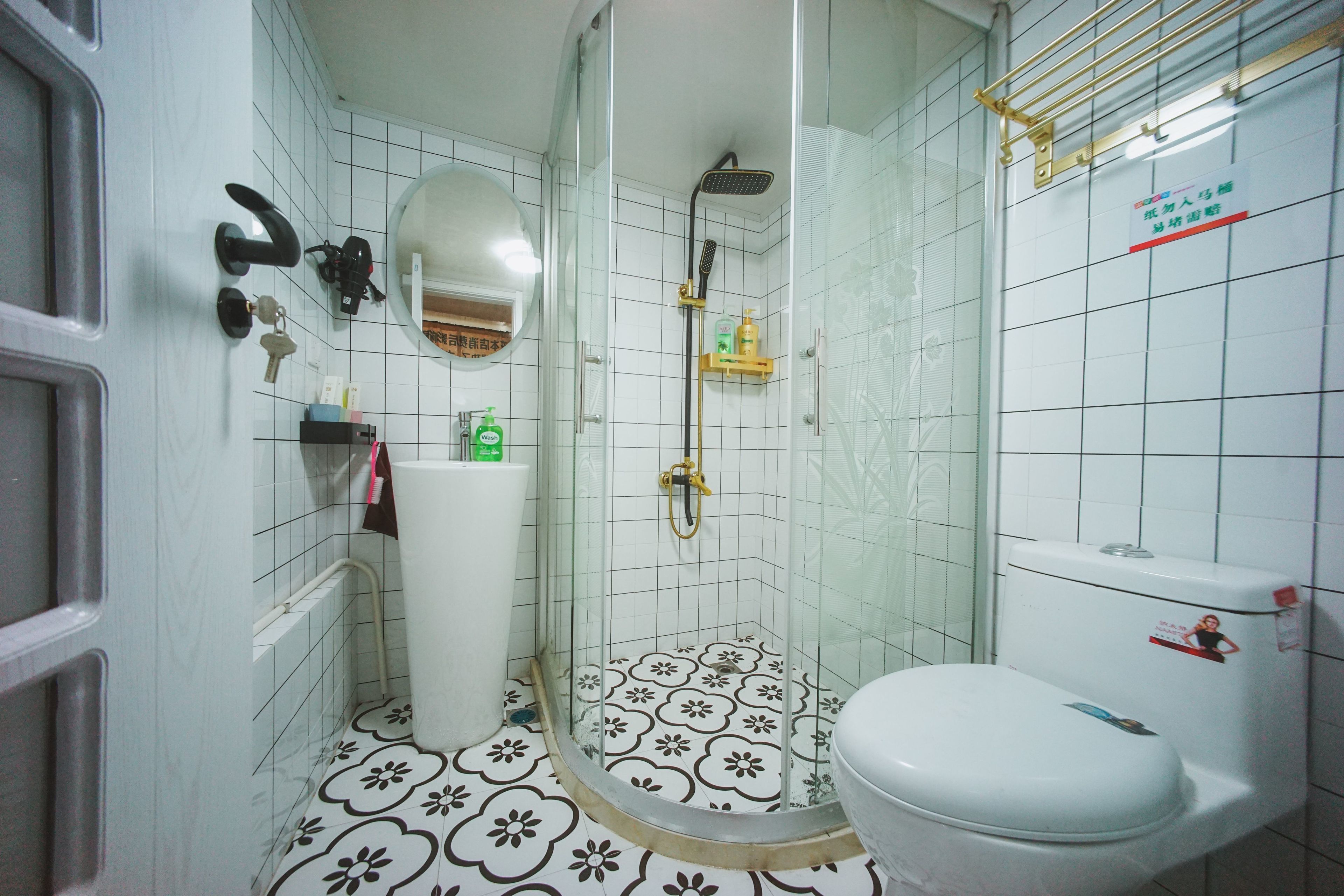 Et badeværelse med toilet, brusebad og håndvask.