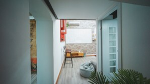 A narrow hallway with a wooden floor, a white door on the right, and a small seating area with a chair and a bean bag. - Shanghai Rainbow No.35 (Shanghai)