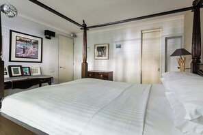 A bedroom with a four-poster bed, a desk with a chair, a nightstand, and two framed pictures on the wall. - Holland Park Avenue VII by Onefinestay (London)