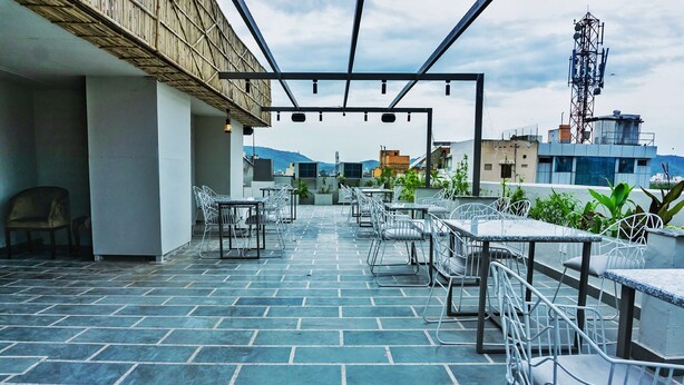 Un espacio al aire libre con patio, piso de baldosas, sillas y mesas de metal.