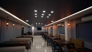 Un restaurante con una barra larga, varias mesas y lámparas colgantes.
