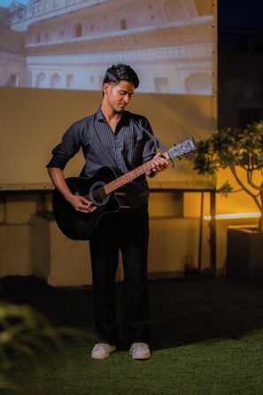 Eine Person spielt nachts im Freien Gitarre.