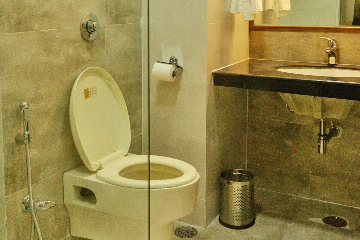 Ein modernes Badezimmer mit einer gläsernen Dusche, einer weißen Toilette, einem Waschbecken und einem Spiegel.