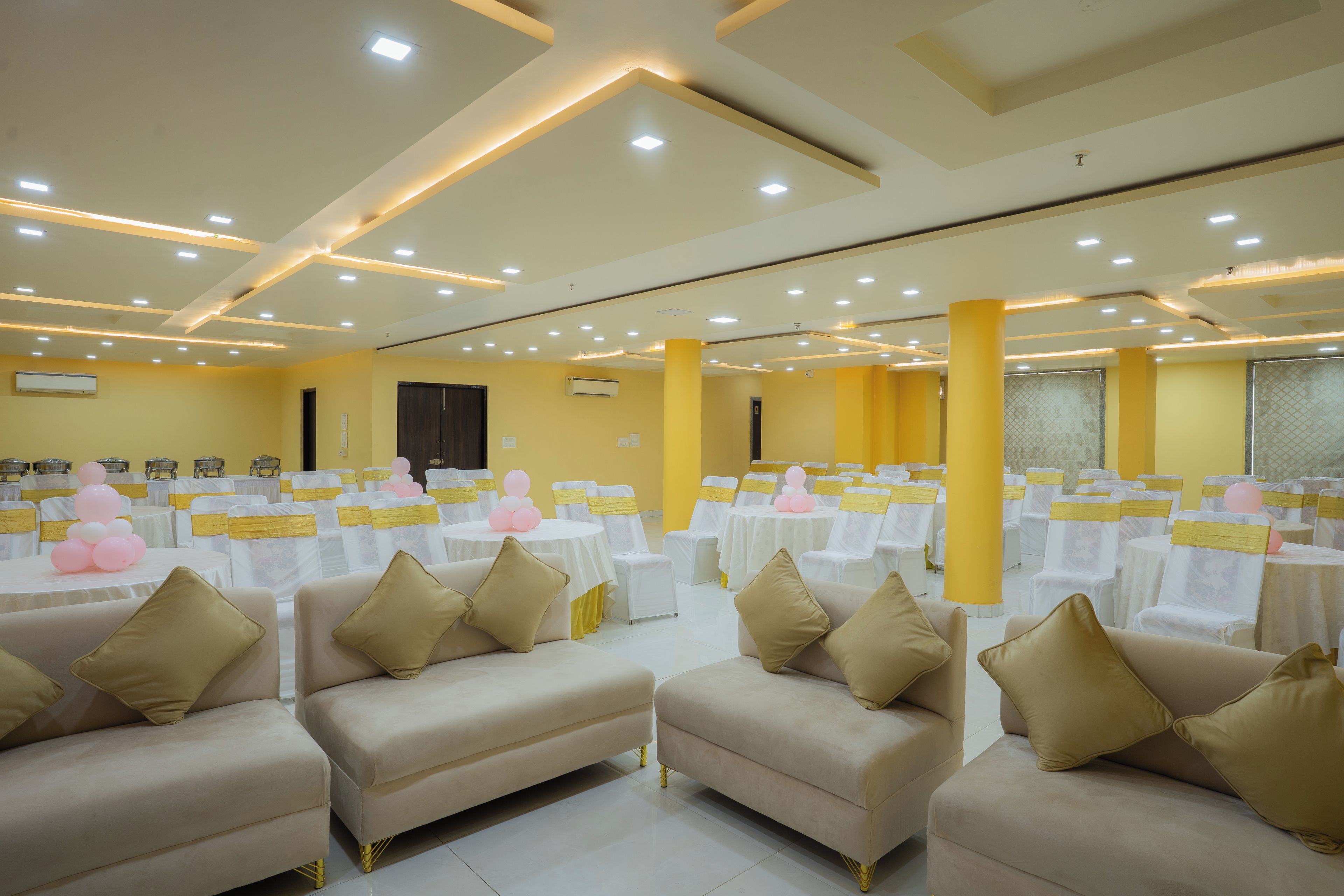 A banquet hall with round tables, chairs, and sofas arranged for an event.